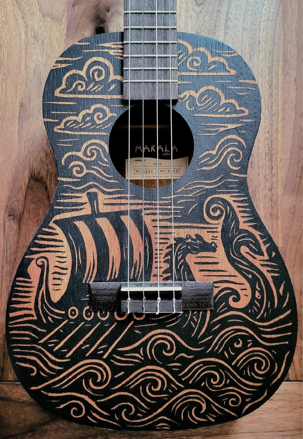 A baritone ukulele with custom Norse longship artwork applied to the body