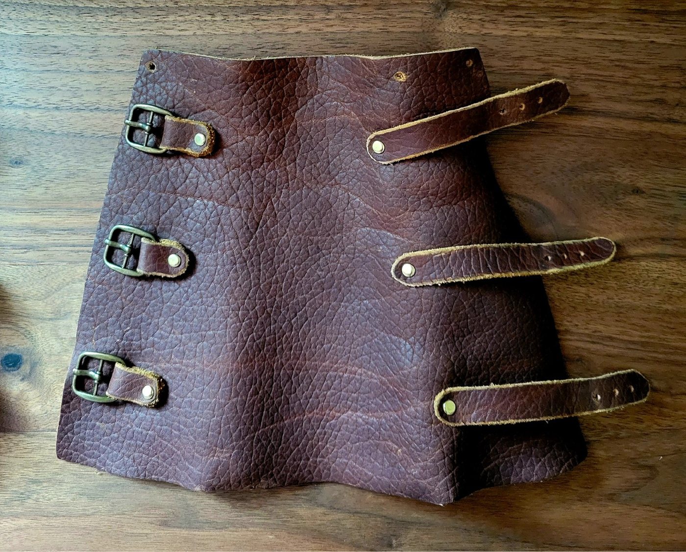 A pair of hand-tooled leather bracers laid flat showing the carved surface detail